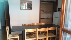 A dining area with a table and chairs, a kitchen in the background, and a framed picture on the wall. - Da Elena Apartment, two-room apartment with private garden, complex with pool and tennis court (Pacengo)