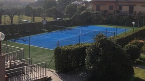 A tennis court surrounded by greenery and residential buildings. - Da Elena Apartment, two-room apartment with private garden, complex with pool and tennis court (Pacengo)