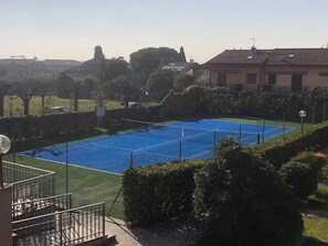 A tennis court surrounded by greenery and residential buildings. - Da Elena Apartment, two-room apartment with private garden, complex with pool and tennis court (Pacengo)