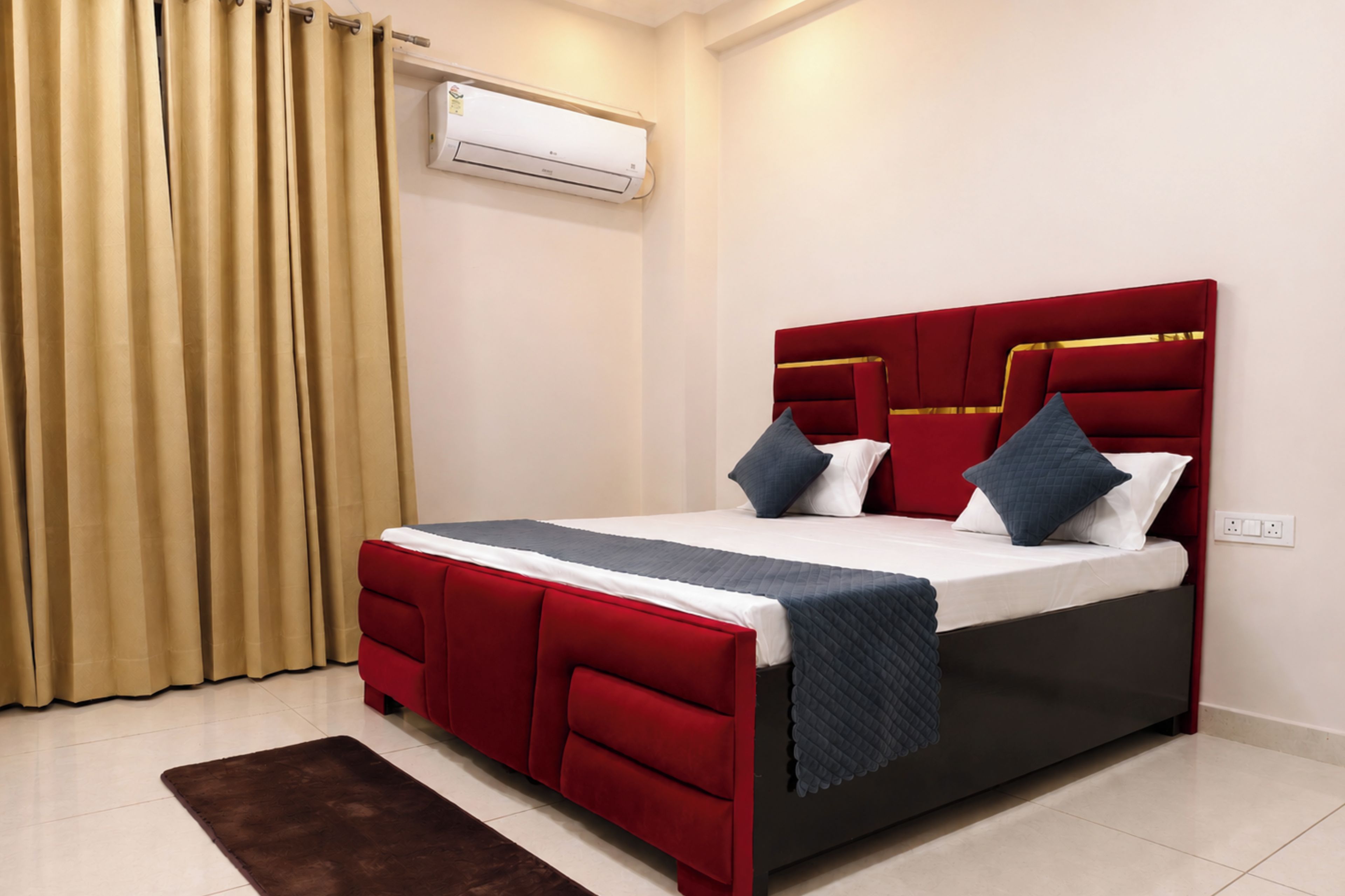 Habitación de hotel con cama, cortinas, aire acondicionado y una alfombra marrón.