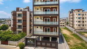 A multi-story hotel with balconies, air conditioning units, and a sign indicating the name 'AARMBH.' - Aarambh Hillside View (Dehradun)