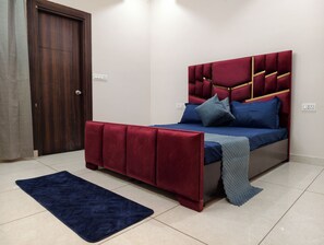 Un dormitorio con una cama, un tapete azul oscuro y una puerta de madera.
