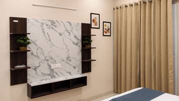 A bedroom with a bed, a marble wall unit, and a window with curtains.