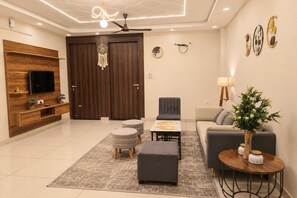 A modern living room with a flat-screen TV, a sofa, a coffee table, and a decorative plant. - Aarambh Hillside View (Dehradun)