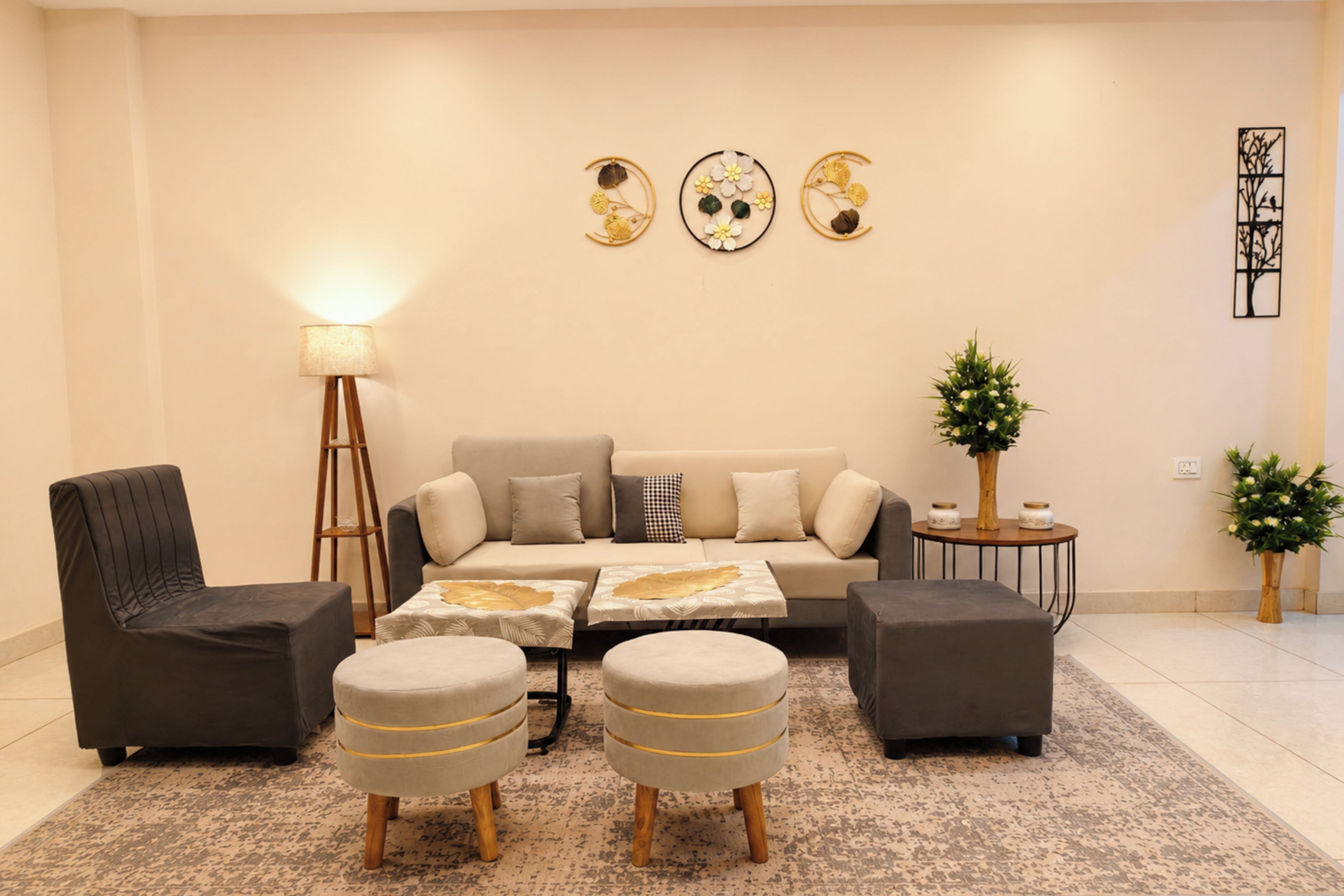 Una sala de estar con un sofá, dos otomanas, una lámpara de pie y decoración en la pared.