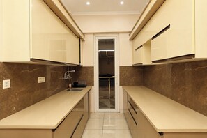 A narrow kitchen with two counters, a sink, and cabinets. - Aarambh Hillside View (Dehradun)