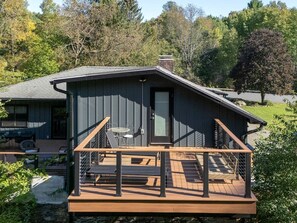Eine Hütte mit einer Terrasse, einem überdachten Sitzbereich im Freien und Blick auf den umliegenden Wald.