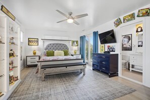 Ein Schlafzimmer mit Bett, Deckenventilator, Fernseher, Kommode und Kleiderschrank.