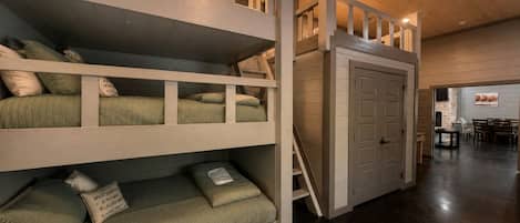 A multi-level bunk bed room with a staircase leading to a door.