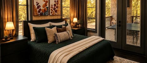 A bedroom with a large bed, two bedside tables with lamps, a view of the outdoors through a sliding glass door, and artwork on the wall.
