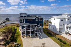A two-story house with a balcony, a dock, and a view of the water. - Incredible Spacious Beach House with Stunning Views for an Amazing Family Getaway in Corolla, North Carolina (Corolla)