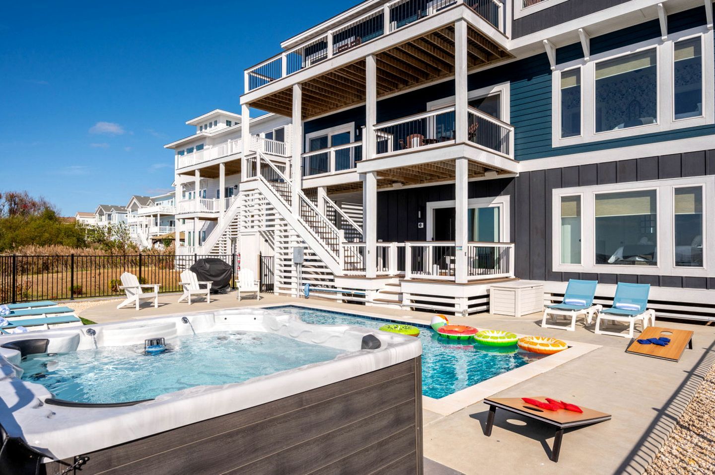 A multi-story building with a swimming pool, outdoor seating, and a covered deck area.