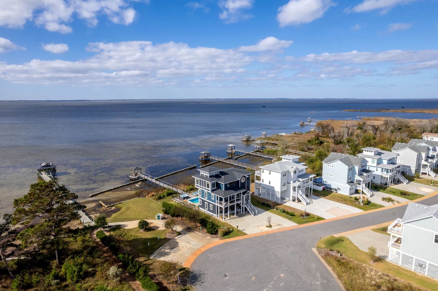 A coastal residential area with houses, a dock, and a clear view of the sea.