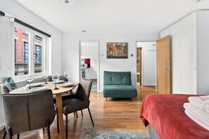 Ein modernes Zimmer mit Esstisch, Stühlen, einer Couch, einem Bett und einem Bild an der Wand.