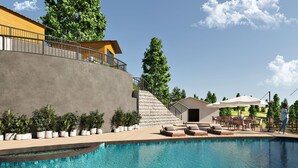 Une piscine avec des chaises longues, un petit bâtiment et un escalier menant à un balcon.