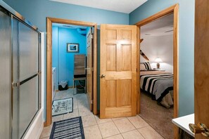 A hallway with a wooden door leading to a bedroom with a bed and a nightstand. - Deluxe Cabin with Three Stunning Decks for a Group Getaway on Norris Lake, Tennessee (Speedwell)
