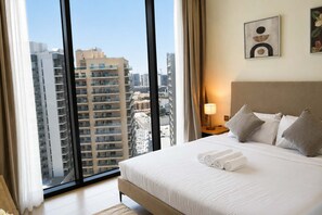 A hotel room with a large bed, a nightstand, a lamp, and a view of tall buildings. - Stylish New 1 bedroom with Private Jacuzzi -Binghatti (Dubai)