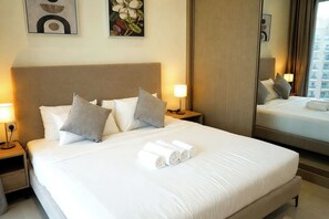 Ein Hotelzimmer mit einem großen Bett, zwei Nachttischen, einem Schminktisch, einem Spiegel und Bildern an den Wänden.