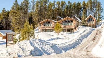 A lodge with multiple wooden cabins, a snow-covered slope, and a clear sky.