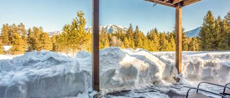 Una estructura de madera con un banco, rodeada de nieve y árboles.