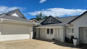 Uma casa com garagem, alpendre coberto e um pequeno jardim.