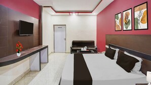 A hotel room with a bed, a desk, a television, and a door. - Classic Hotel Shantila Inn (Prayagraj)