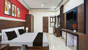A hotel room with a bed, bedside table, TV, and artwork on the wall. - Classic Hotel Shantila Inn (Prayagraj)