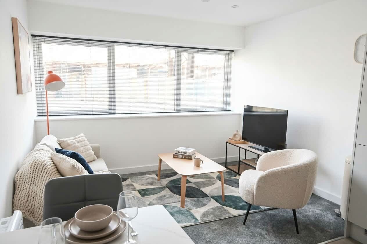 A modern living room with a sofa, a coffee table, a TV, and a chair.