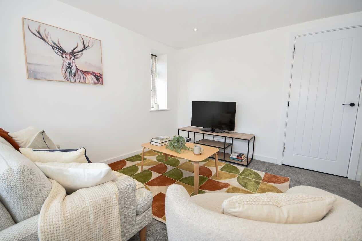 A living room with a sofa, a coffee table, a flat-screen TV, and a door.