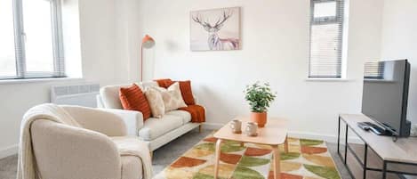 A living room with a sofa, a coffee table, a television, and a painting of a deer.