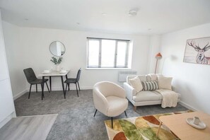 Ein modernes Wohnzimmer mit Essbereich, einer Couch, einem Couchtisch und einem Gemälde an der Wand.