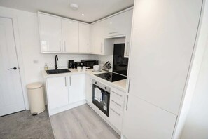 Eine kleine Küche mit weißen Schränken, einer schwarzen Spüle, einer Mikrowelle und einem Backofen.