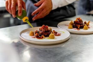 A person pouring sauce onto a dish. - Hotel Riederalm (Leogang)