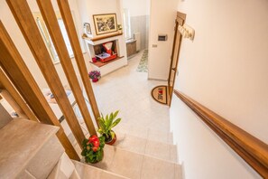 Eine Treppe mit hölzernen Geländern, einem Blumentopf und einer Fußmatte mit dem Aufdruck 'HOME'.