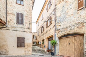 Eine enge Straße mit traditionellen Gebäuden, einer Holztür und einem Blumentopf.