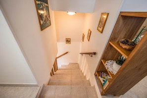 Eine Treppe mit Holzhandläufen, einer Wandleuchte und einem Holzregal mit Dekoration.