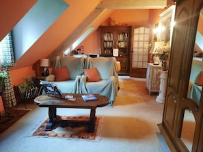 Une pièce mansardée chaleureuse, avec un canapé, une table basse et une bibliothèque.