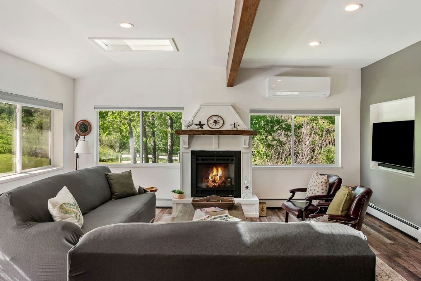 A modern living room with a fireplace, large windows, and a flat-screen TV.