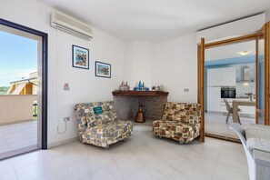 Un soggiorno con due poltrone a motivi, un camino e vista sulla cucina.