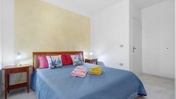 Ein Schlafzimmer mit einem Bett, zwei Nachttischen und einer Tür.