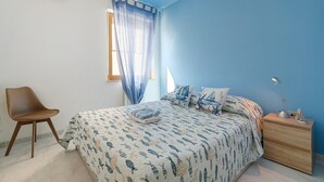Une chambre à coucher avec un lit, une chaise, une table de chevet et une fenêtre avec des rideaux.
