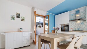 Une cuisine moderne avec un mur d’accent bleu, une table à manger en bois et un meuble blanc avec des tiroirs.