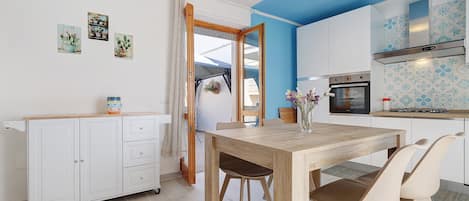 A modern kitchen with a blue accent wall, a wooden dining table, and a white cabinet with drawers.