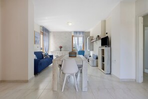 A modern living room with a dining table, a sofa, and a TV. - Apartment 'Casa Mariposa- Alghero' with Private Terrace, Wi-Fi and Air Conditioning (Alghero)