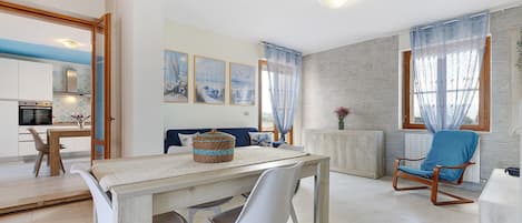A modern living room with a dining area, a blue chair, and artwork on the wall.