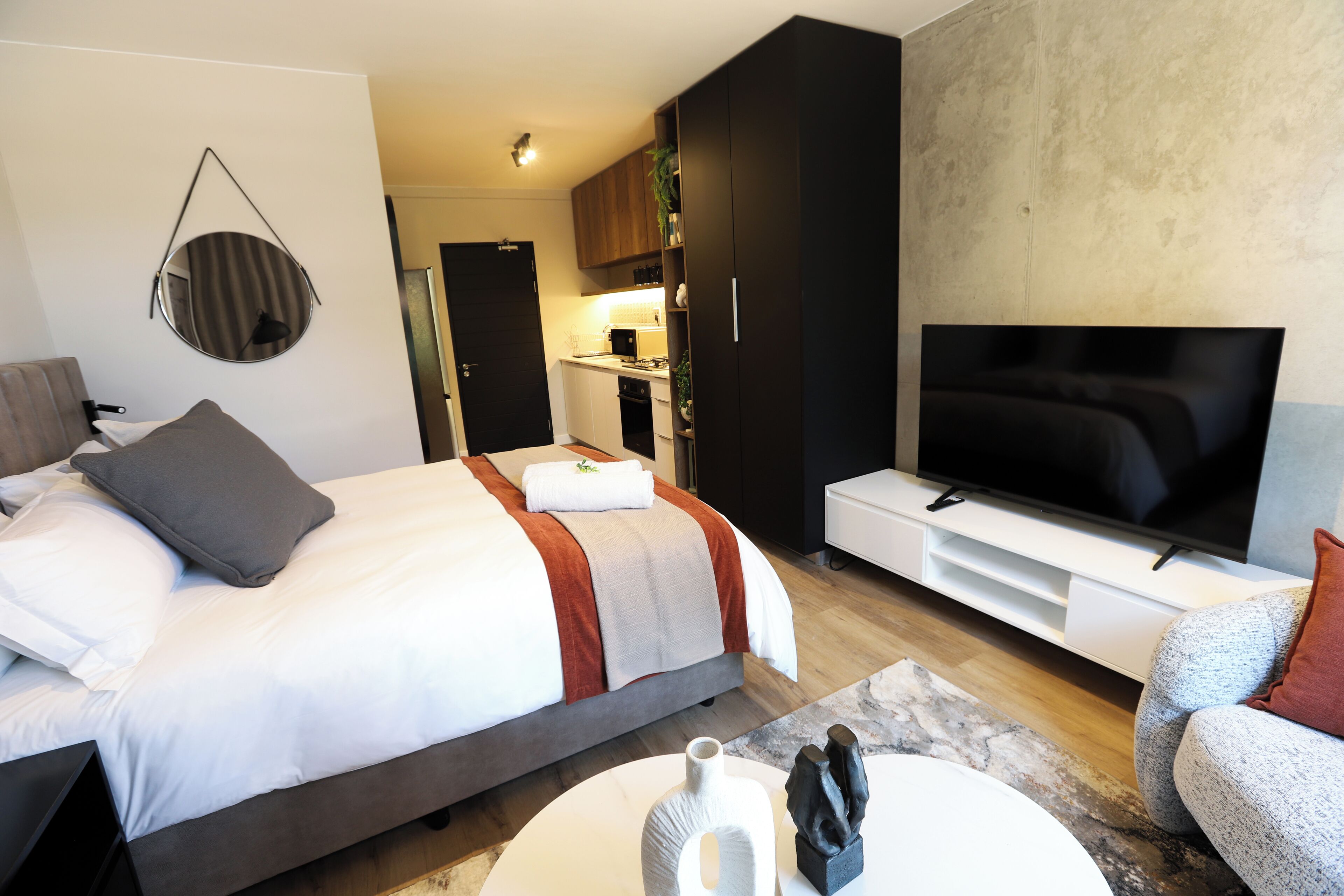 Une chambre d’hôtel moderne équipée d’un lit, d’une télévision et d’une kitchenette.