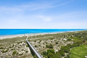 Eine Küstenlandschaft mit Brücke, Strand und spärlicher Vegetation.