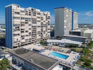 A multi-story hotel with a rooftop pool area, surrounded by other buildings. - Newly renovated luxury retreat with incredible views, features 6 bedrooms and 5 baths! (Ocean City)