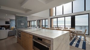 A modern kitchen with a large island, wooden cabinets, and a view of the sea. - Newly renovated luxury retreat with incredible views, features 6 bedrooms and 5 baths! (Ocean City)