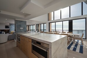 A modern kitchen with a large island, wooden cabinets, and a view of the sea. - Newly renovated luxury retreat with incredible views, features 6 bedrooms and 5 baths! (Ocean City)